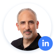 Homem com cabelos grisalhos, camisa preta, ícone do LinkedIn.